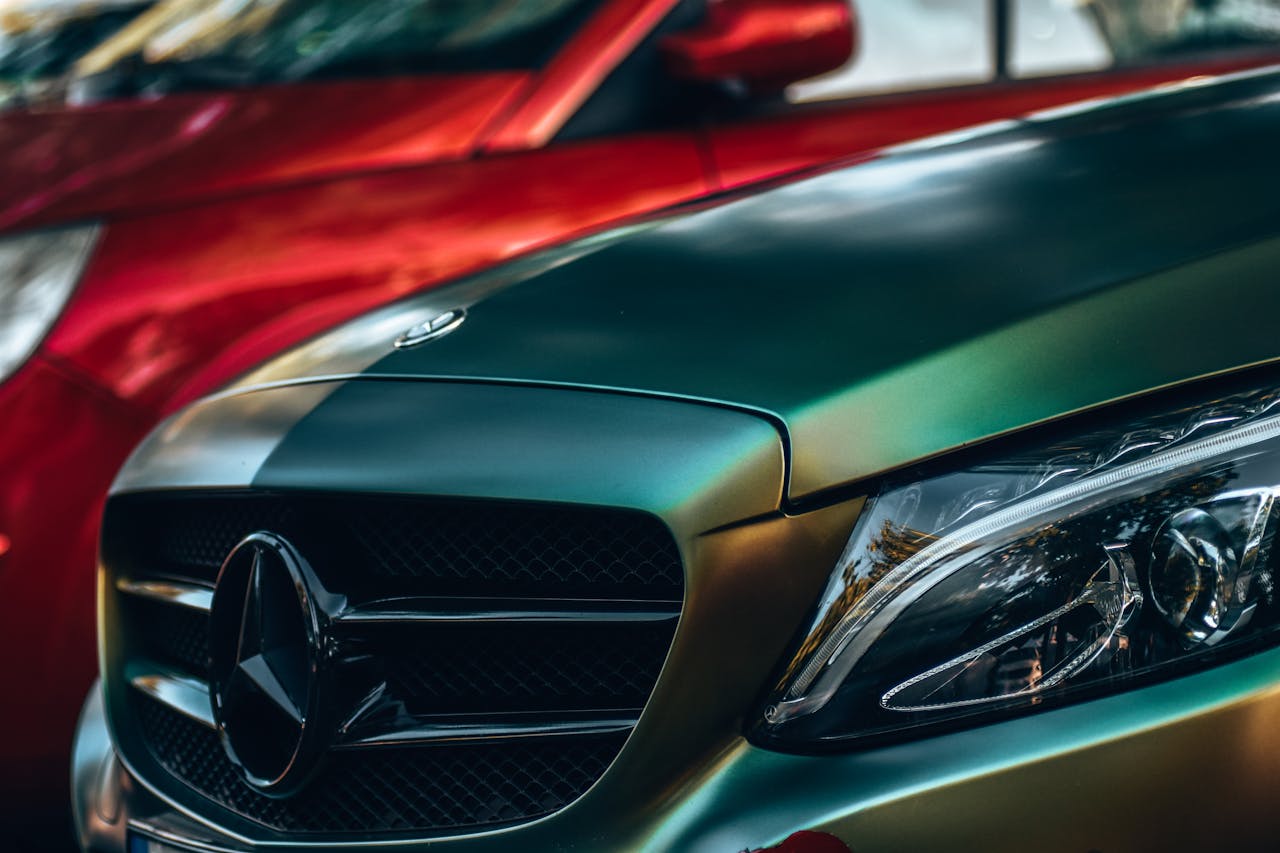 Detailed view of a luxury Mercedes Benz with focus on the emblem and headlight.